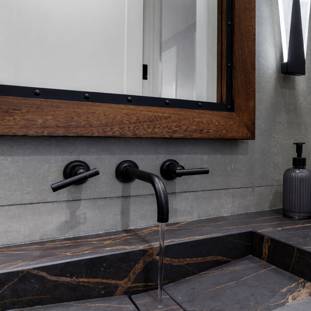 Matte black wall-mounted faucet detail on veined stone counter