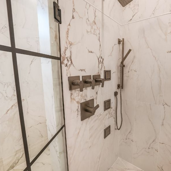 Marble-look tiled shower with black-framed glass enclosure