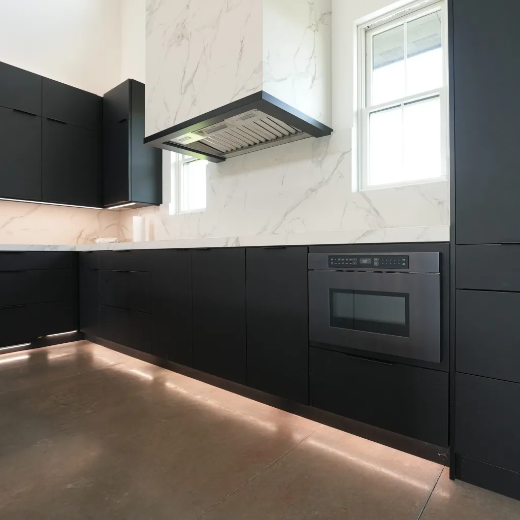 Black cabinetry run with integrated appliances and stone backsplash